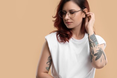 Photo of Beautiful tattooed woman on beige background, space for text