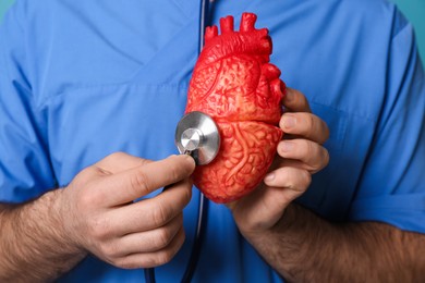 Doctor with stethoscope and model of heart, closeup. Cardiology concept