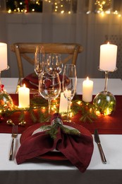 Photo of Christmas table setting with burning candles and festive decor