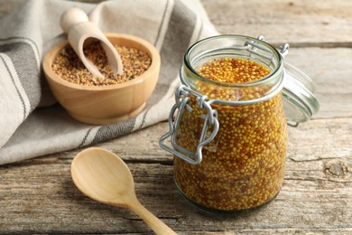 Photo of Whole grain mustard in jar and spoon on wooden table