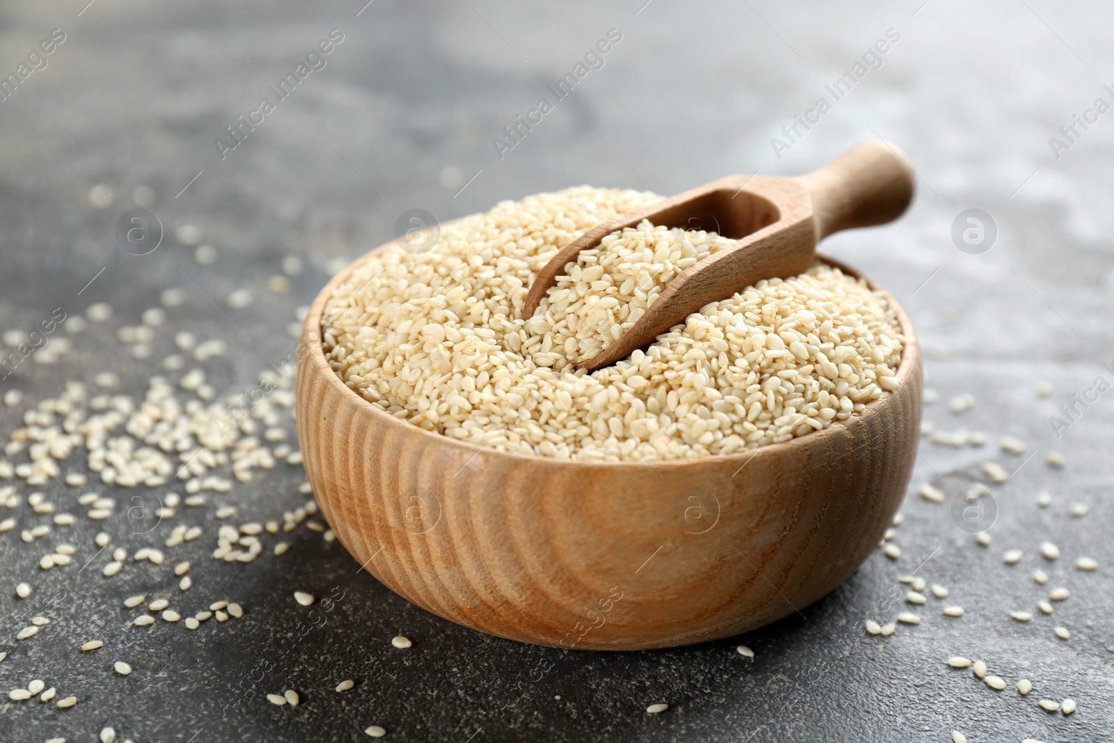 Photo of Bowl and scoop with white sesame seeds on grey table