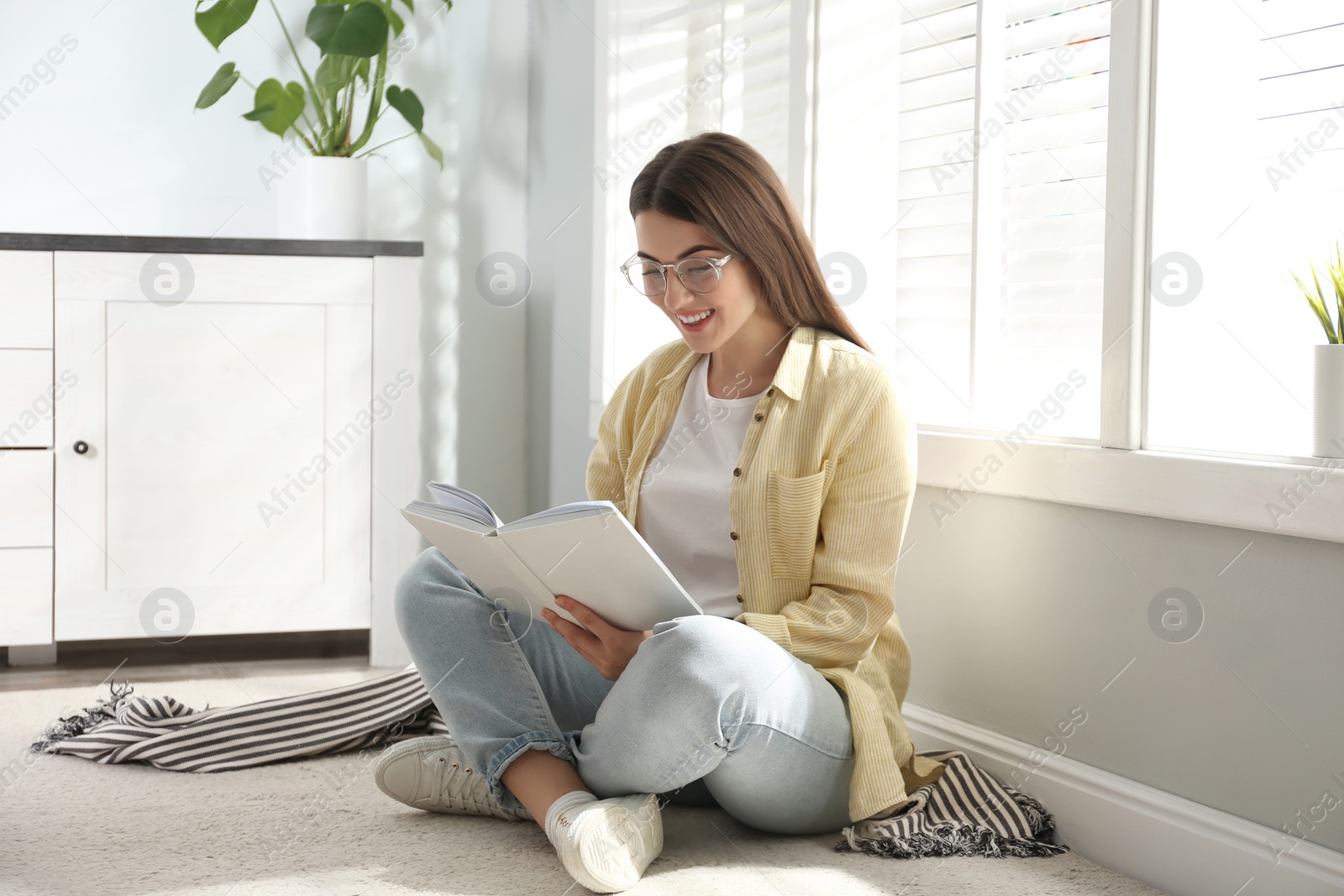 Photo of Beautiful young woman reading book at home