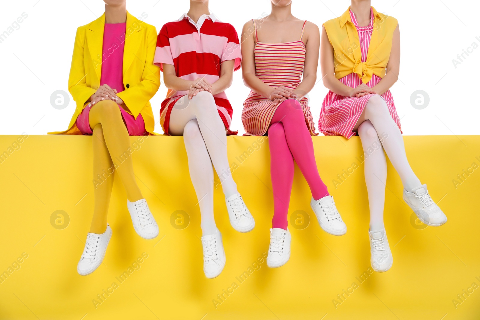 Photo of Women wearing bright tights sitting on color background, closeup