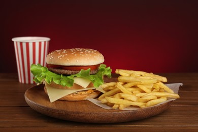 Delicious fast food menu on wooden table against red background