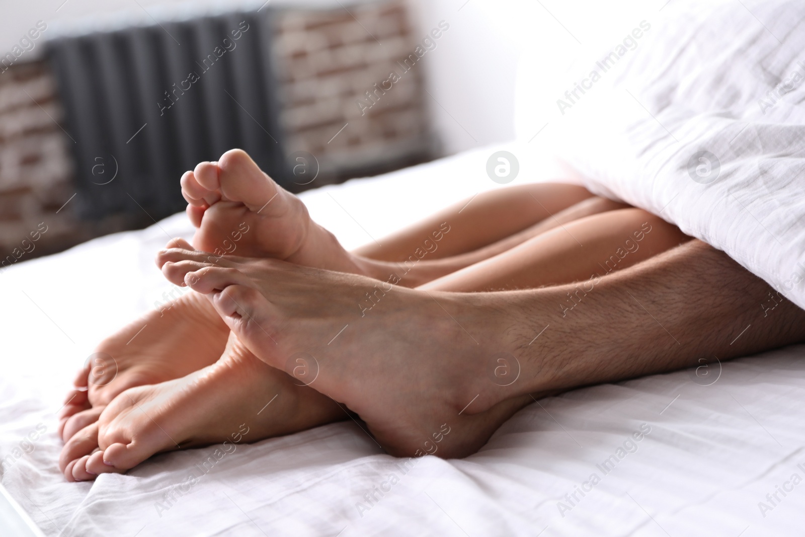 Photo of Passionate young couple having sex on bed at home, closeup of legs