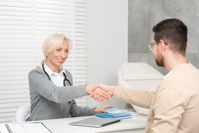 Doctor shaking hands with patient after consultation in clinic