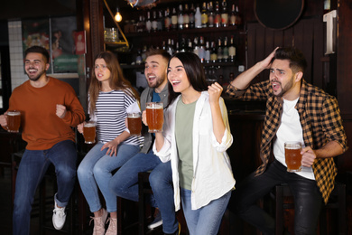 Group of friends watching football in sport bar