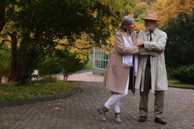 Photo of Affectionate senior couple in autumn park, space for text
