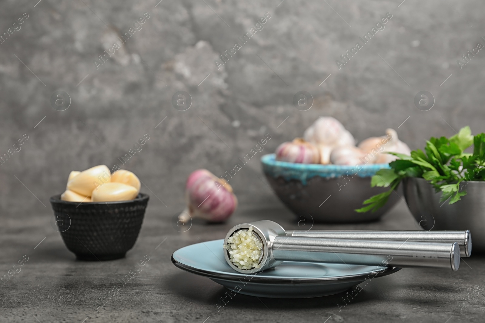 Photo of Garlic press with crushed clove on table. Kitchen utensil