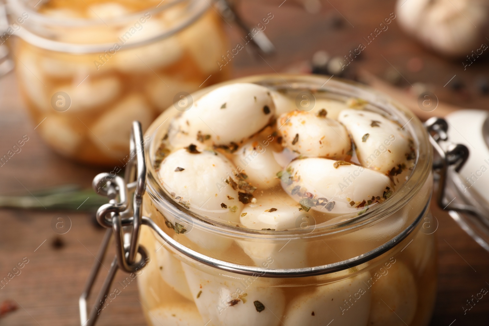 Photo of Preserved garlic in glass jar on wooden table, closeup