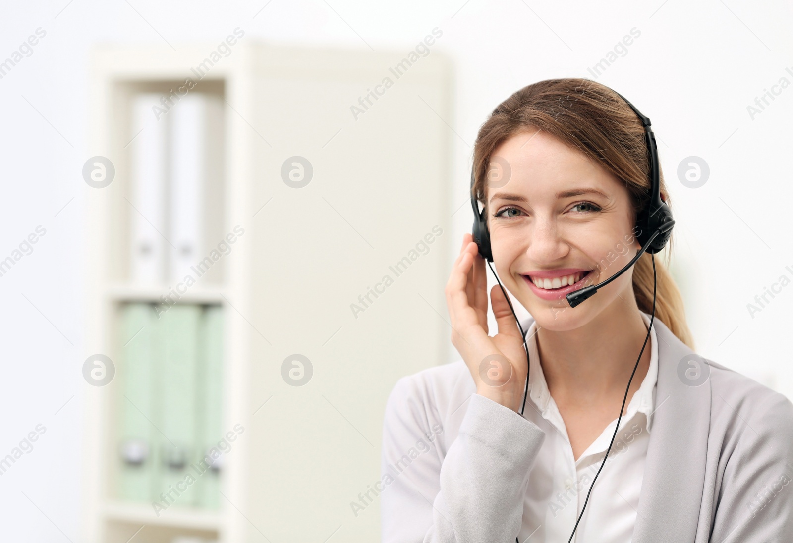 Photo of Young female receptionist with headset in office