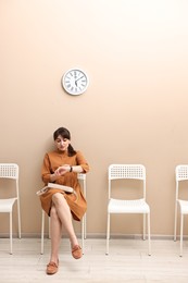 Woman looking at wrist watch and waiting for appointment indoors