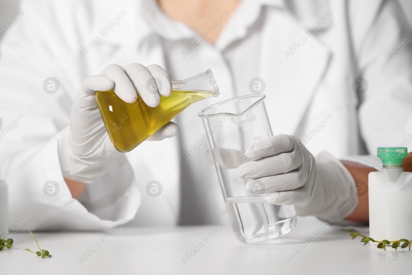 Photo of Dermatologist developing cosmetic product at white table, selective focus