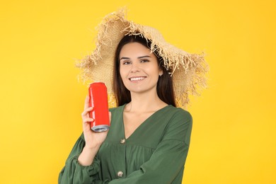 Beautiful happy woman holding red beverage can on yellow background