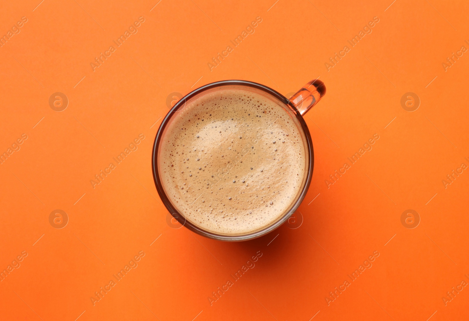 Photo of Fresh coffee in cup on orange background, top view