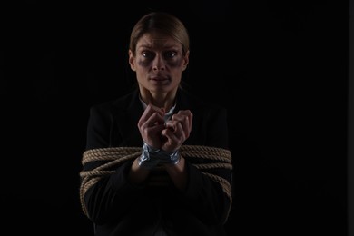 Photo of Scared woman tied up and taken hostage on dark background