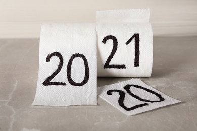 Photo of Toilet paper with numbers 2020 and 2021 on light grey marble background. New year concept