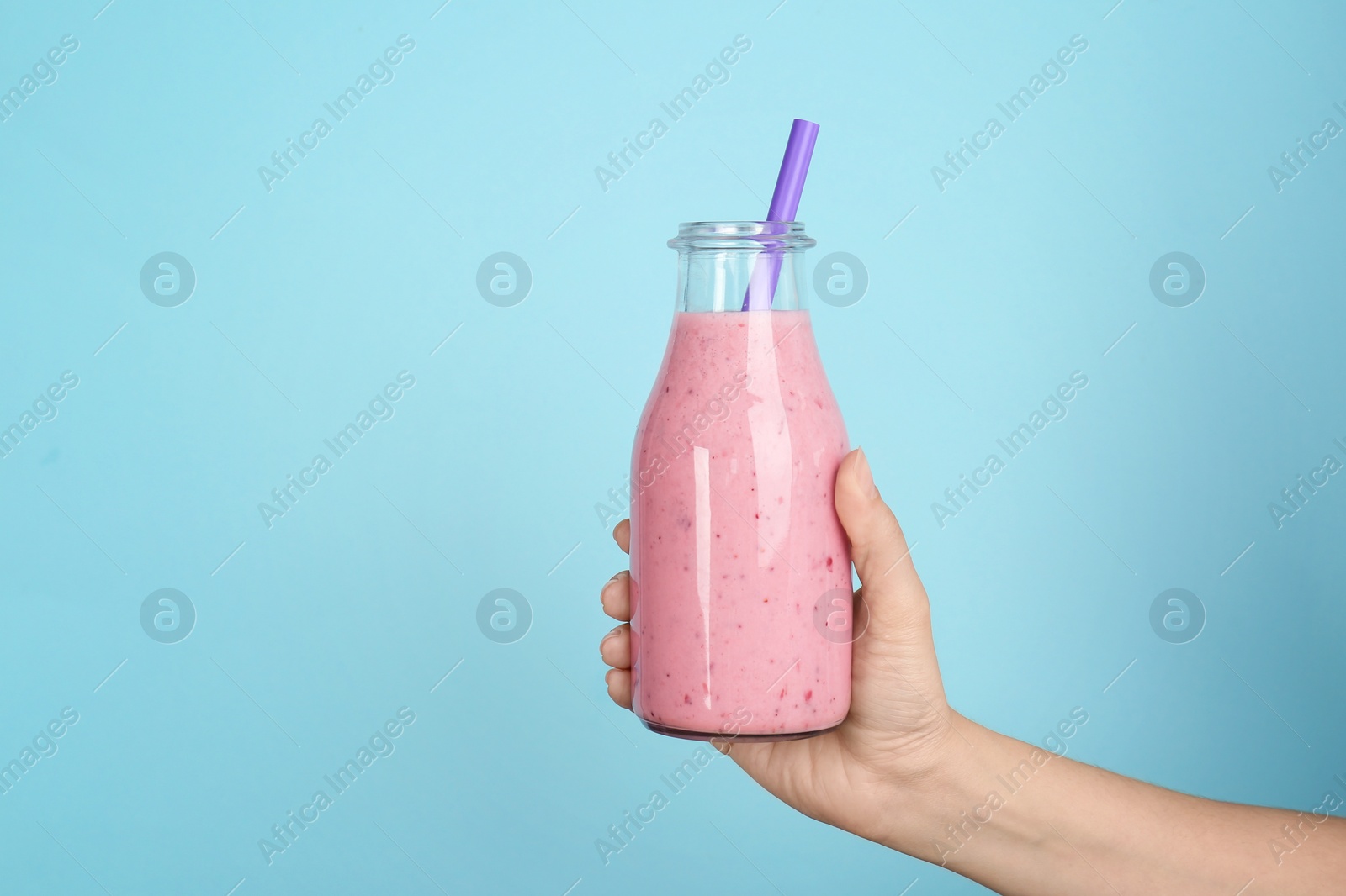 Photo of Woman holding bottle with delicious smoothie on color background