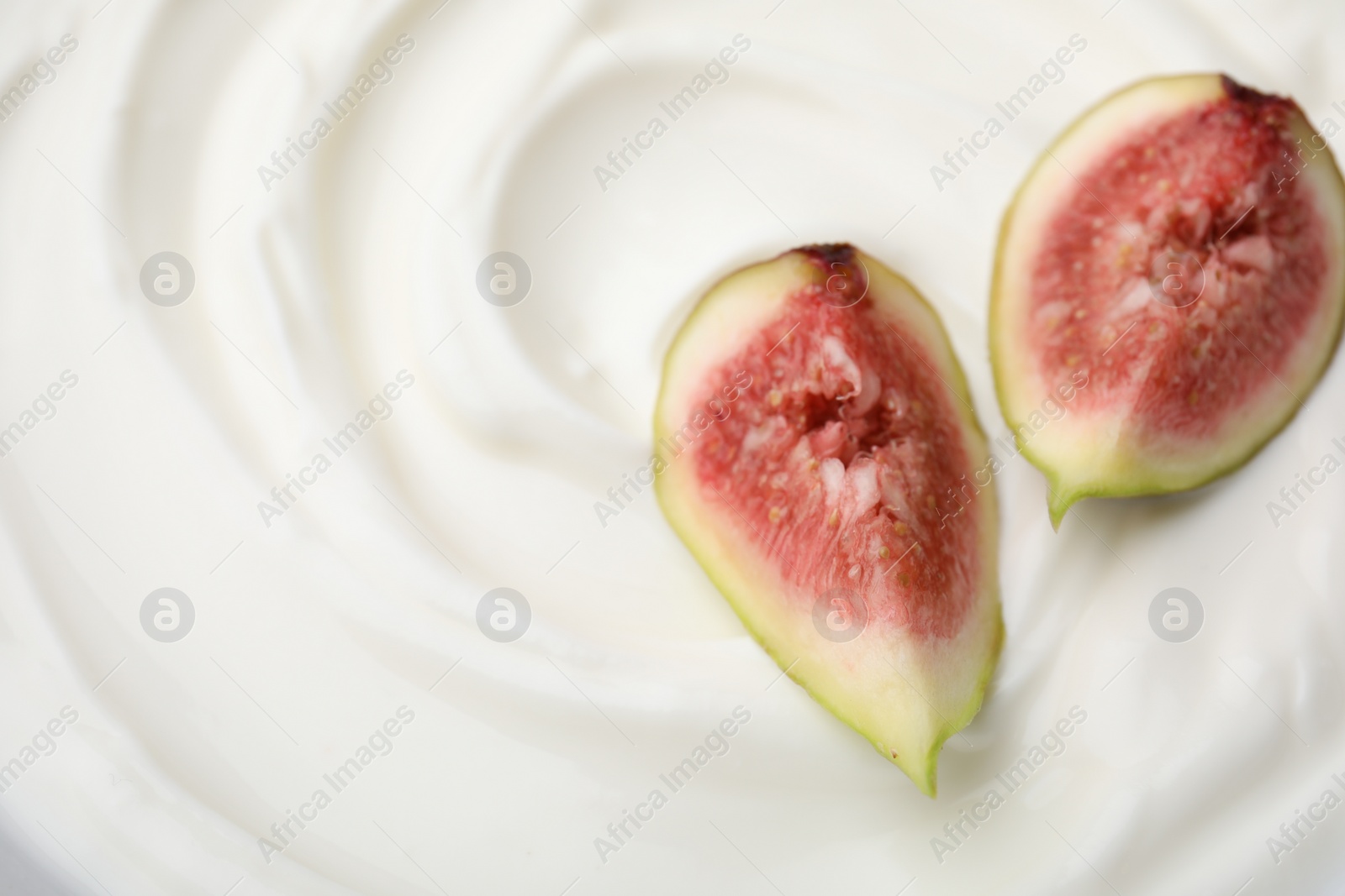 Photo of Tasty yogurt with cut fig as background, top view. Space for text