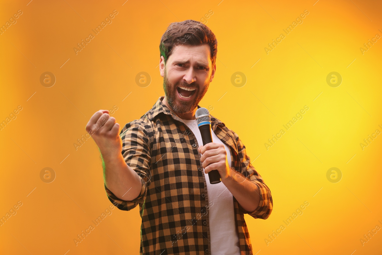 Photo of Handsome man with microphone singing on golden background