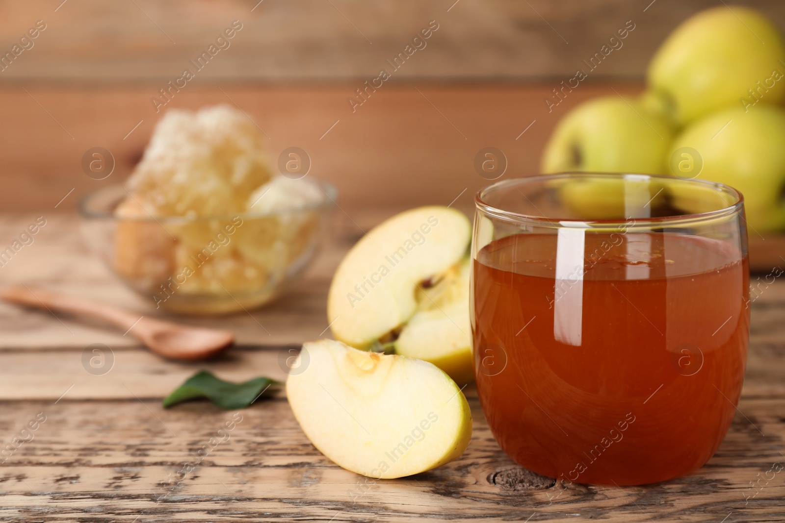 Photo of Glass of honey and apples on wooden table