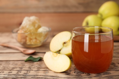 Glass of honey and apples on wooden table