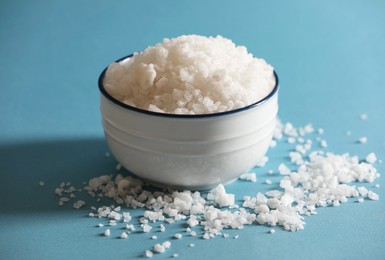 Photo of Organic salt in bowl on light blue background, closeup