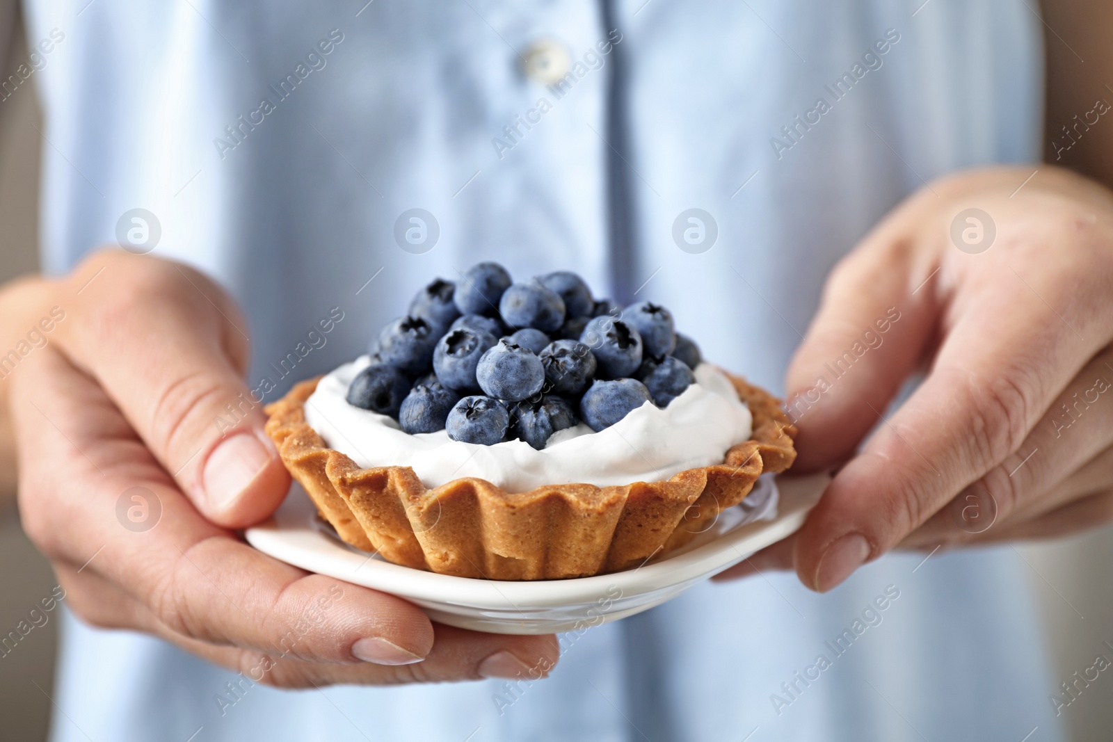 Photo of Woman holding plate with blueberry tart, closeup. Delicious pastries