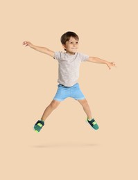 Image of Happy boy jumping on beige background, full length portrait