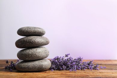 Photo of Lavender flowers and spa stones on wooden table. Space for text