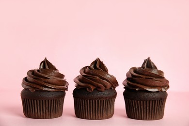 Photo of Delicious chocolate cupcakes with cream on pink background. Space for text