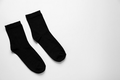 Pair of black socks on white background, flat lay. Space for text