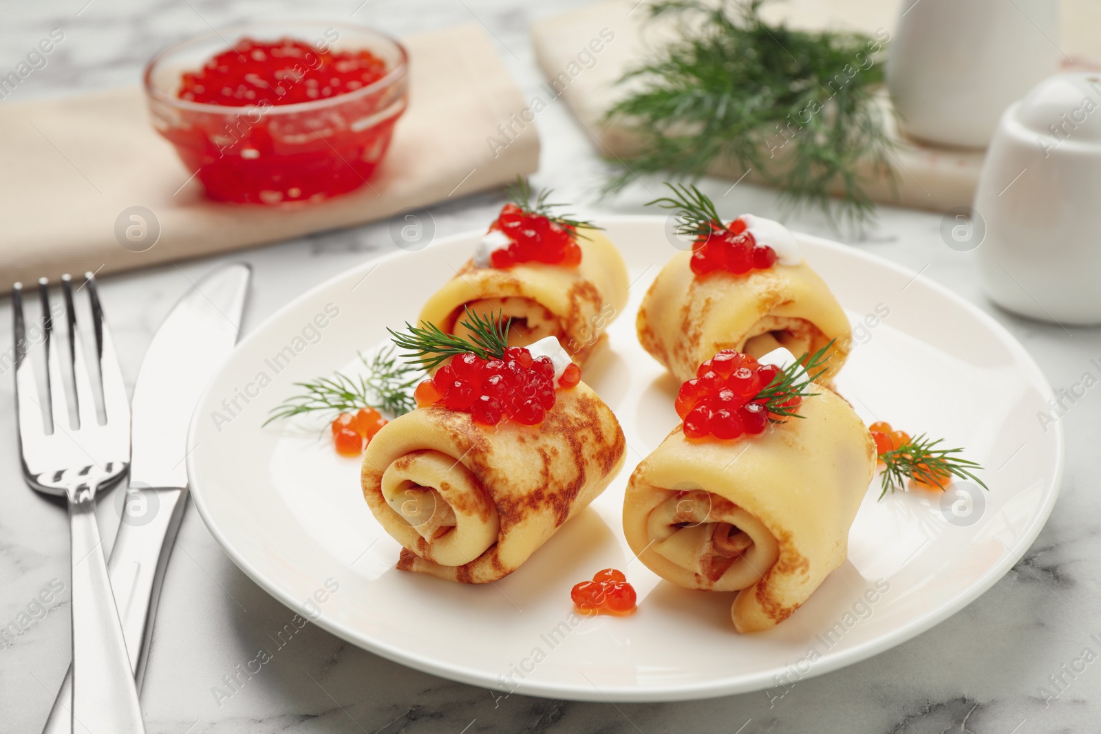 Photo of Delicious thin pancakes with red caviar on white marble table