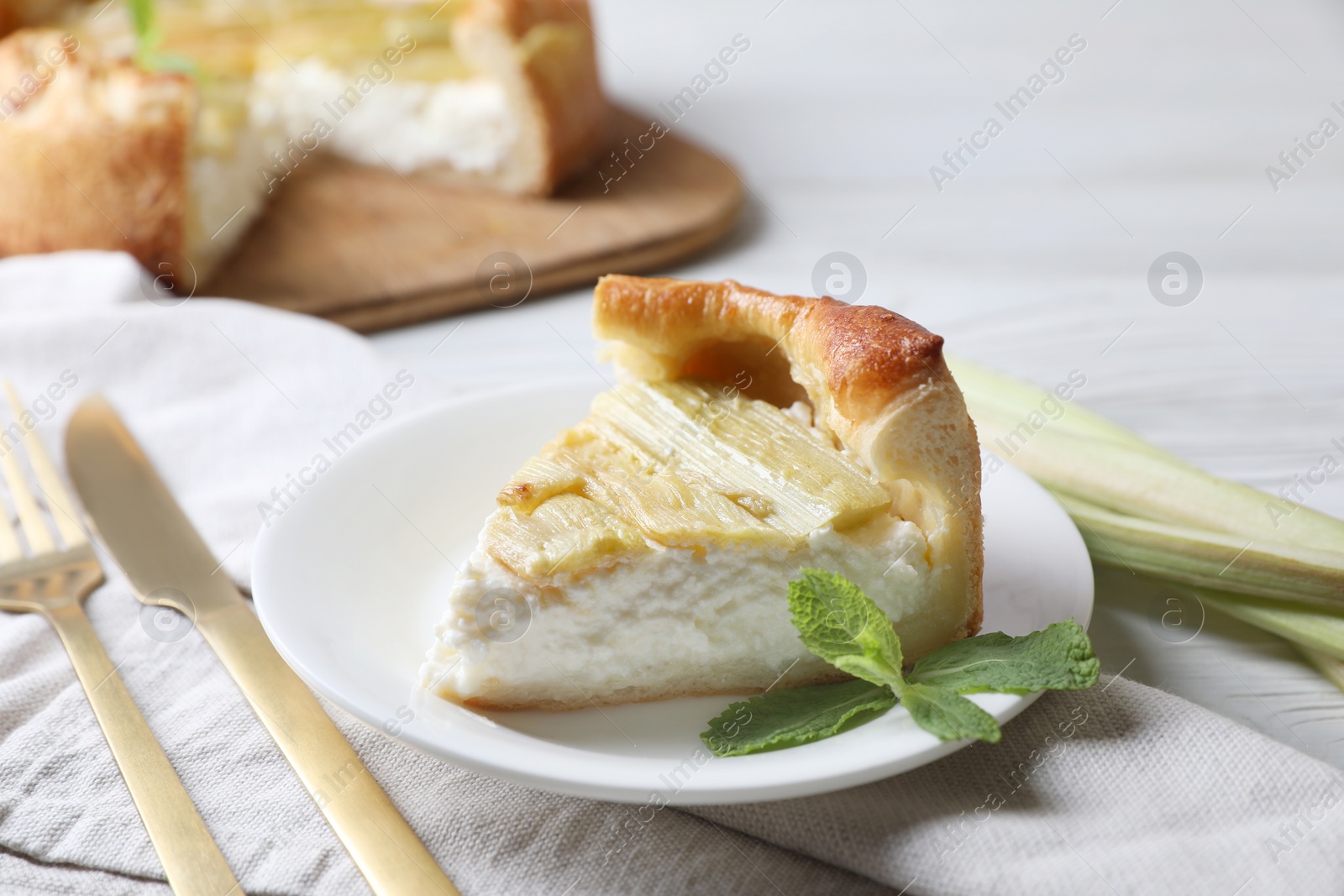 Photo of Piece of freshly baked rhubarb pie with cream cheese and cutlery on table, closeup