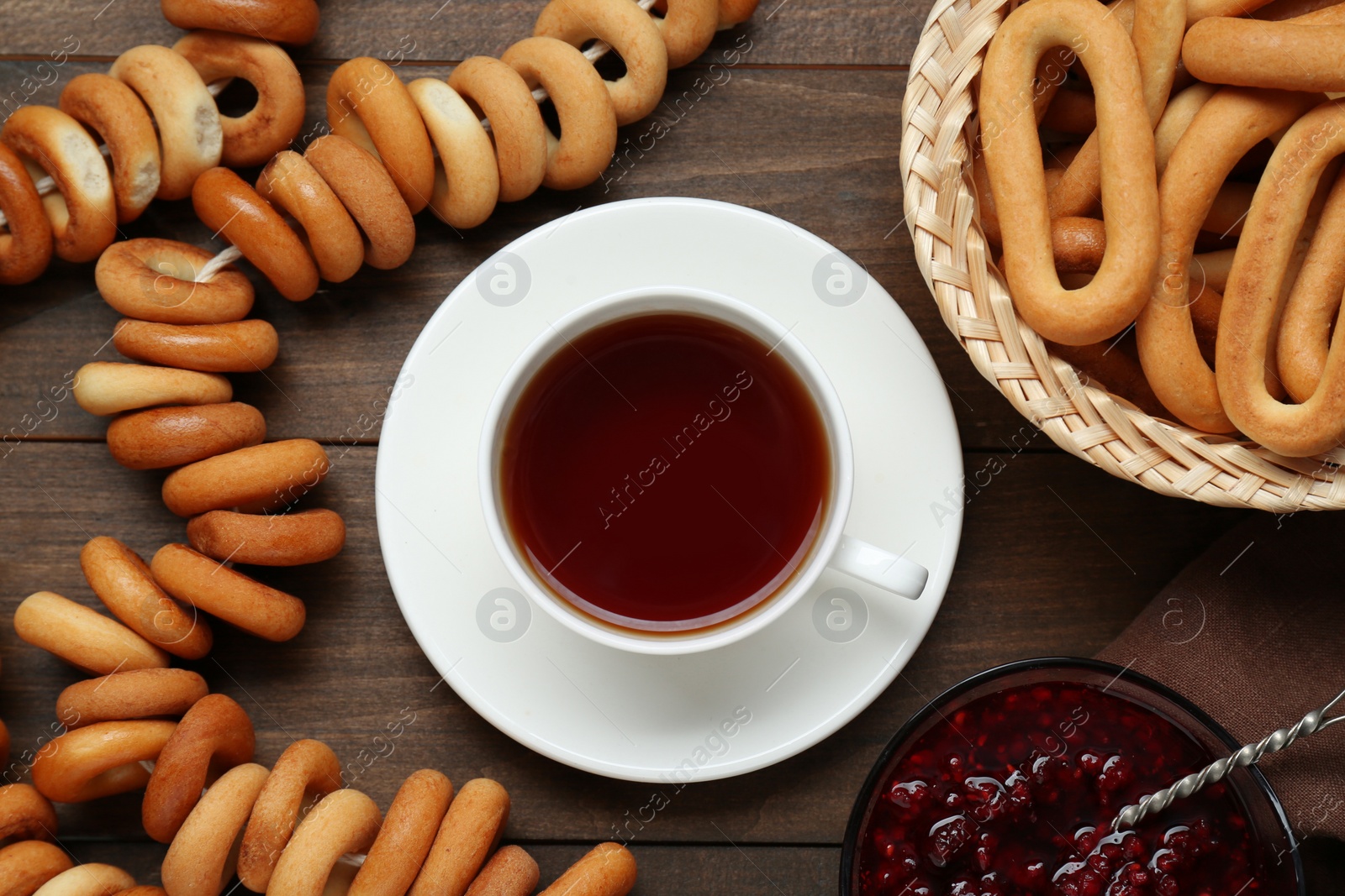 Photo of Flat lay composition with delicious ring shaped Sushki (dry bagels) and cup of tea on wooden table