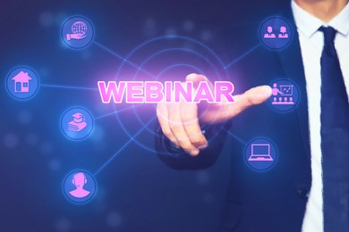 Webinar. Businessman using virtual screen with icons on blue background, closeup