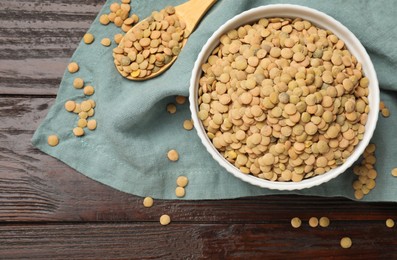 Photo of Raw lentils in bowl and spoon on wooden table, top view