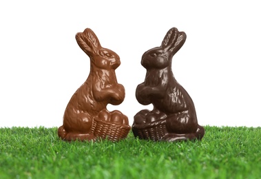 Chocolate bunnies on green grass against white background. Easter celebration