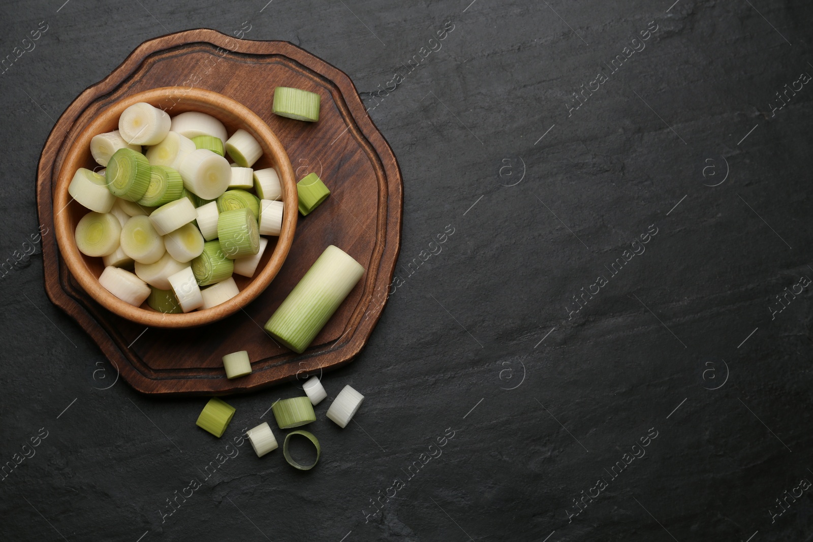 Photo of Cut fresh raw leek on black table, flat lay. Space for text