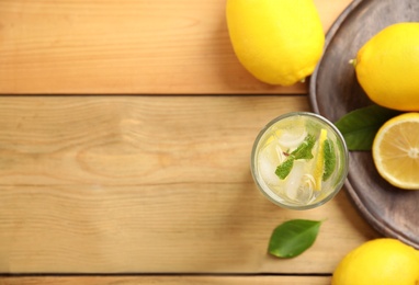 Photo of Cool freshly made lemonade and fruits on wooden table, flat lay. Space for text