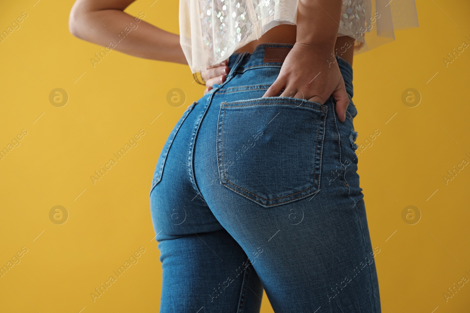 Photo of Woman wearing jeans on yellow background, closeup