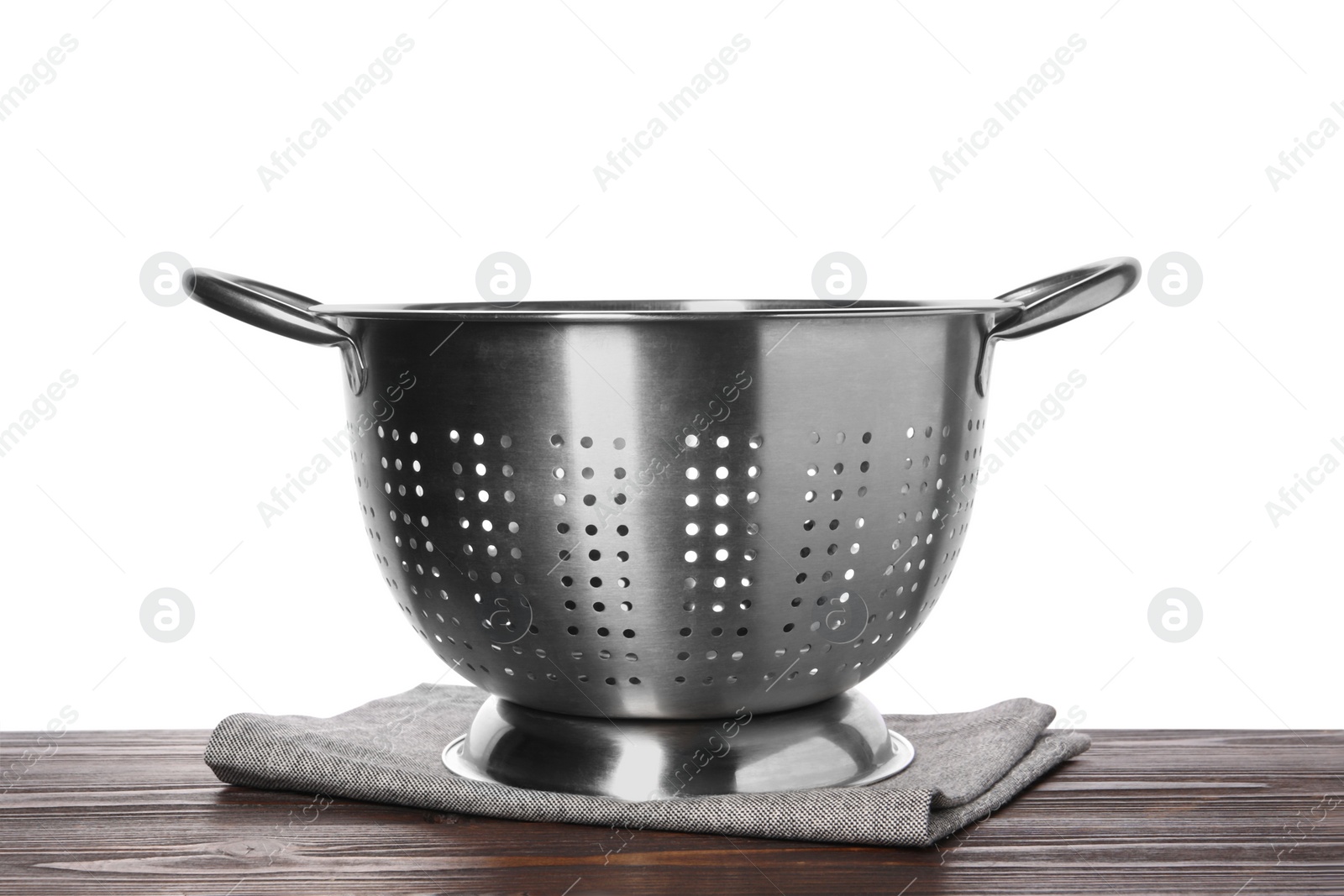 Photo of Metal colander and napkin on wooden table against white background