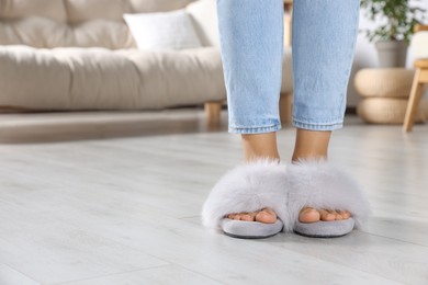 Photo of Woman wearing soft slippers at home, closeup of legs