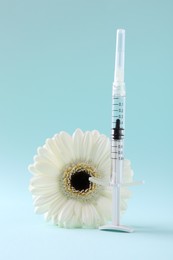 Photo of Cosmetology. Medical syringe and gerbera flower on light blue background