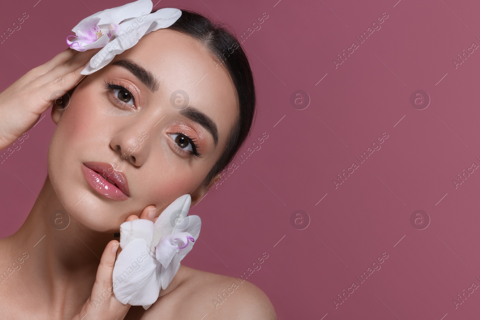 Photo of Portrait of beautiful young woman with orchid flowers on dark pink background. Space for text