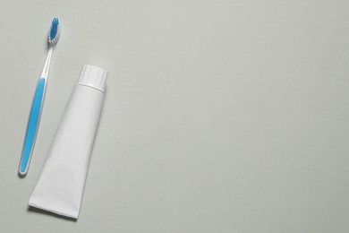 Plastic toothbrush and paste on grey background, flat lay. Space for text