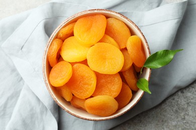 Photo of Bowl of tasty apricots on grey table, top view. Dried fruits