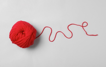 Photo of Soft red woolen yarn on white background, top view