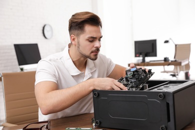 Male technician repairing computer at table indoors