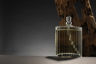 Luxury men`s perfume in bottle on grey table, space for text